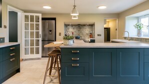 A modern kitchen with dark cabinetry, a central island, and a large window providing natural light.