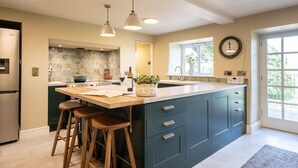 A modern kitchen with a large island, bar stools, and a clock on the wall.