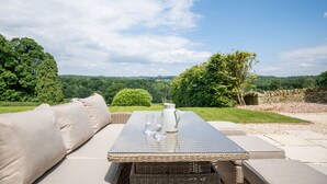 An outdoor seating area with a table, cushions, and a pitcher.