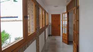 A corridor with wooden doors, a window with a view of a building, and a small table with a plant. - Apartment 'Loft' with Shared Terrace, Wi-Fi and Air Conditioning (Córdoba)