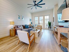 A spacious living room with a sofa, armchair, coffee table, and a ceiling fan.