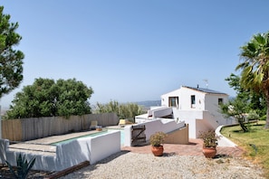 Eine weiße Villa mit Swimmingpool, kleinem Garten und Meerblick.
