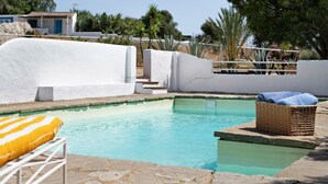 A swimming pool with a wicker basket and a yellow-striped cushion.