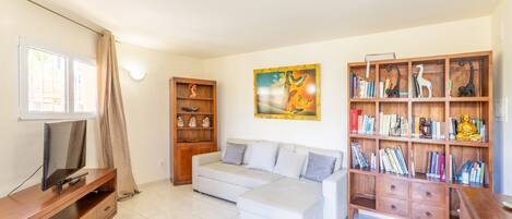 A living room with a sofa, TV stand, bookshelf, and artwork.