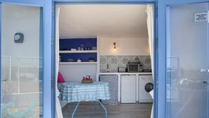 Une pièce comprenant un lit, une table recouverte d’une nappe à motifs, un lave-linge et un four à micro-ondes.