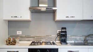 Uma cozinha moderna com armários brancos, fogão a gás, cafeteira e forno embutido.