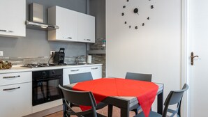 Cozinha moderna com armários brancos, toalha de mesa vermelha e um relógio na parede.