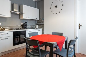 Una cocina moderna con armarios blancos, un mantel rojo y un reloj en la pared.
