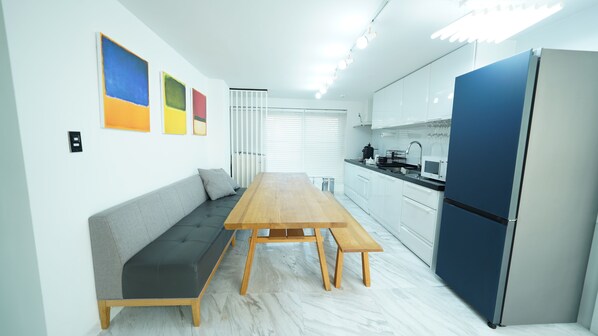 A modern kitchen with white cabinets, a blue refrigerator, and a wooden dining table. - PrivatePremiumSeocho's Happy House 330m2 (Seoul)