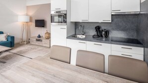A modern kitchen with white cabinets, a built-in oven, and a coffee maker. There is a dining area with a table and chairs. - Holiday Home in Oostkapelle Near the Beach (Oostkapelle)