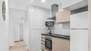 Eine moderne Küche mit weißen Schränken, einer eingebauten Mikrowelle, einem Backofen und einer Edelstahl-Spüle.