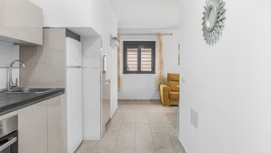 Eine moderne Küche mit weißen Schränken, einer schwarzen Arbeitsplatte und einem Fenster mit Vorhängen.