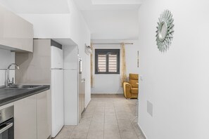 A modern kitchen with white cabinets, a black countertop, and a window with curtains.