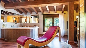 A wooden-framed room with a red cushioned chair, a round rug, and a large mirror.