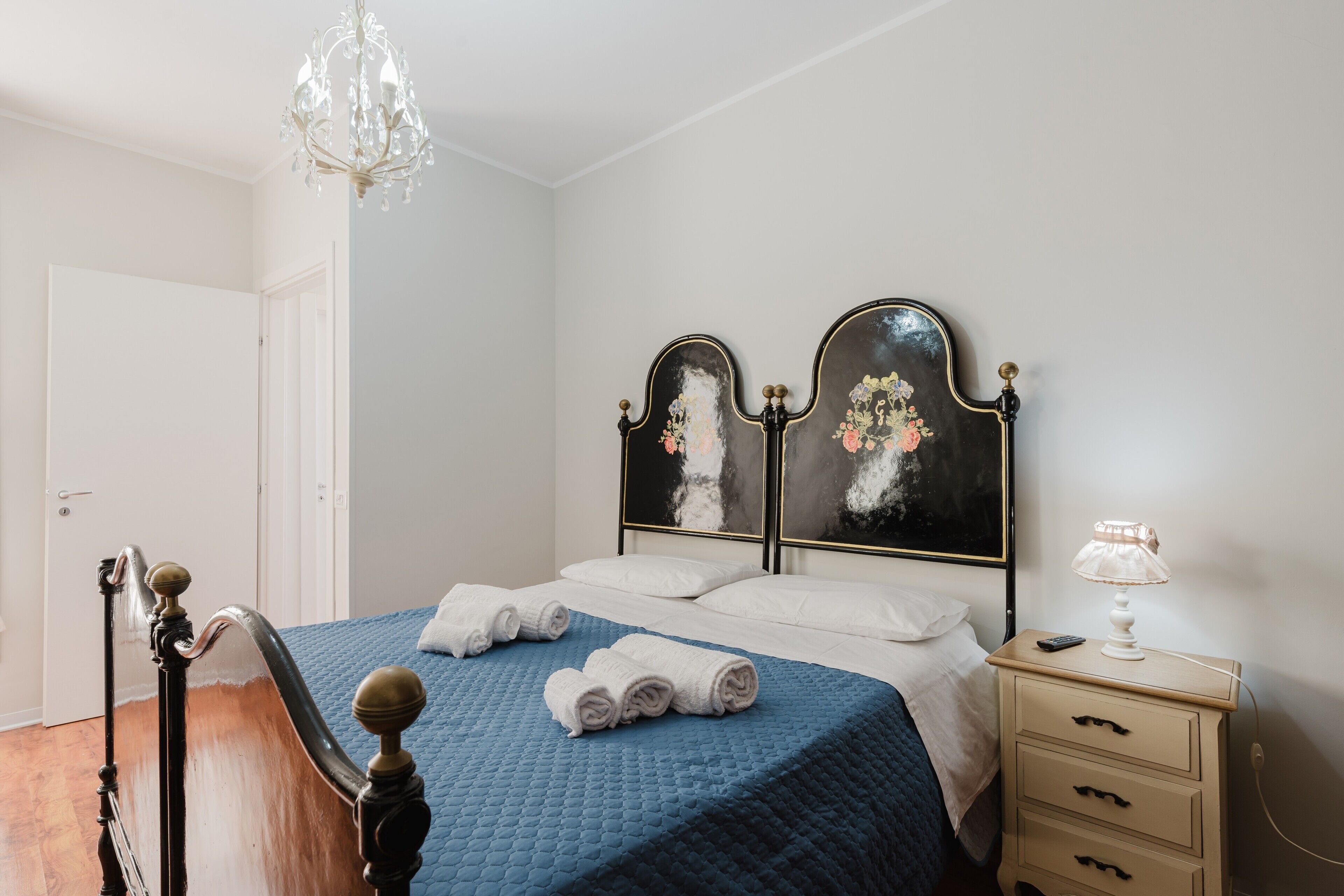 Un dormitorio con cama, mesita de noche, lámpara y candelabro.