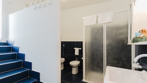 Une salle de bain moderne avec une douche à l’italienne, une baignoire blanche et des toilettes.