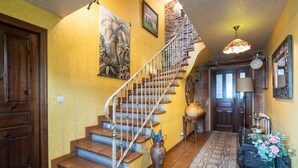 A staircase with a wooden railing, a vase with flowers, and a wall with a painting.