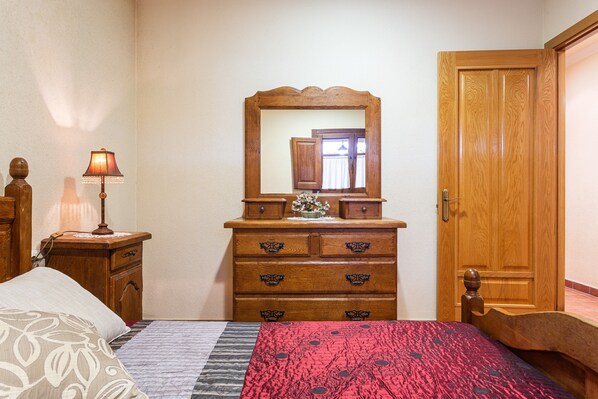 A bedroom with a bed, a dresser, a mirror, and a wooden door. - Country House 'Mas Vila 3' with Mountain View, Wi-Fi and Air Conditioning (Fogars de la Selva)