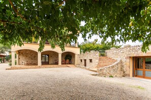A building with a stone facade, arched doorways, and a gravel courtyard. - Country House 'Mas Vila 2' with Mountain View, Wi-Fi and Air Conditioning (Fogars de la Selva)