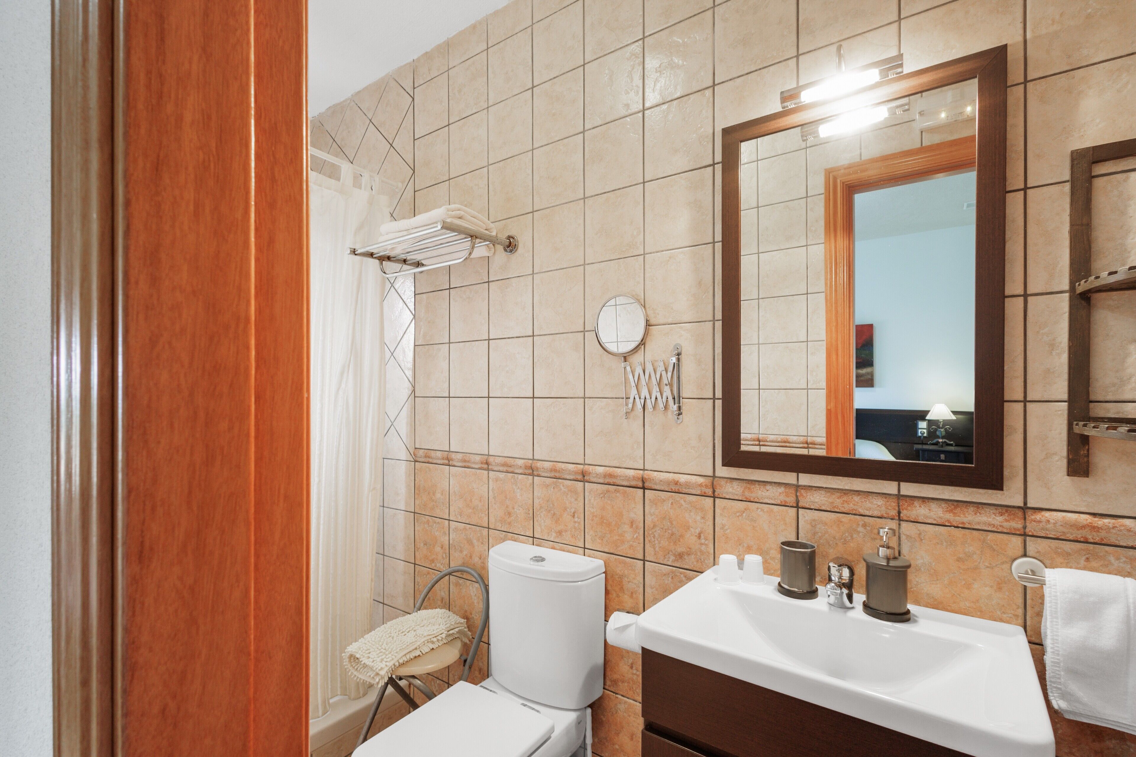 A bathroom with a toilet, sink, mirror, towel rack, and shower curtain.