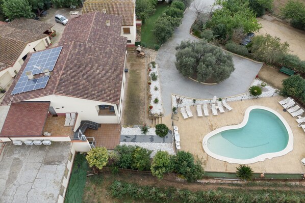 A residential property with a swimming pool, solar panels, and a garden.