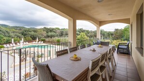 Ein Balkon mit Tisch und Stühlen, ein Pool und Blick auf Grünflächen.