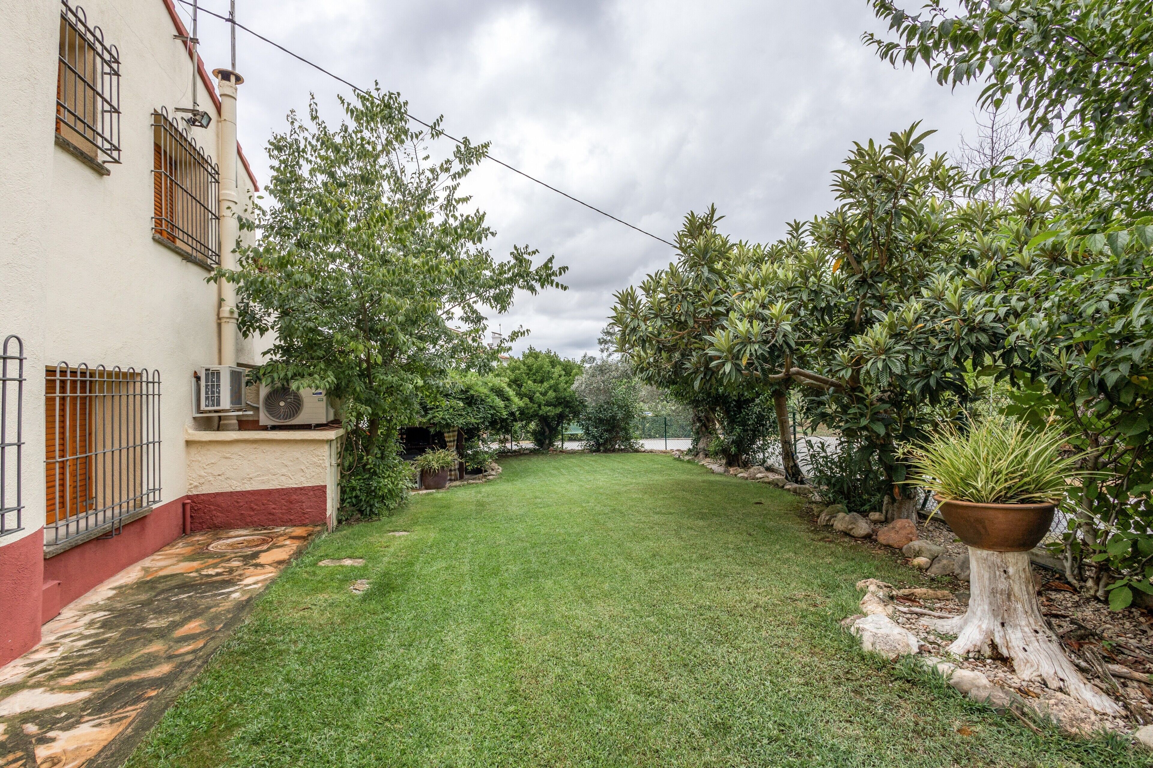 A well-maintained backyard with a lawn, a tree, and a large planter.
