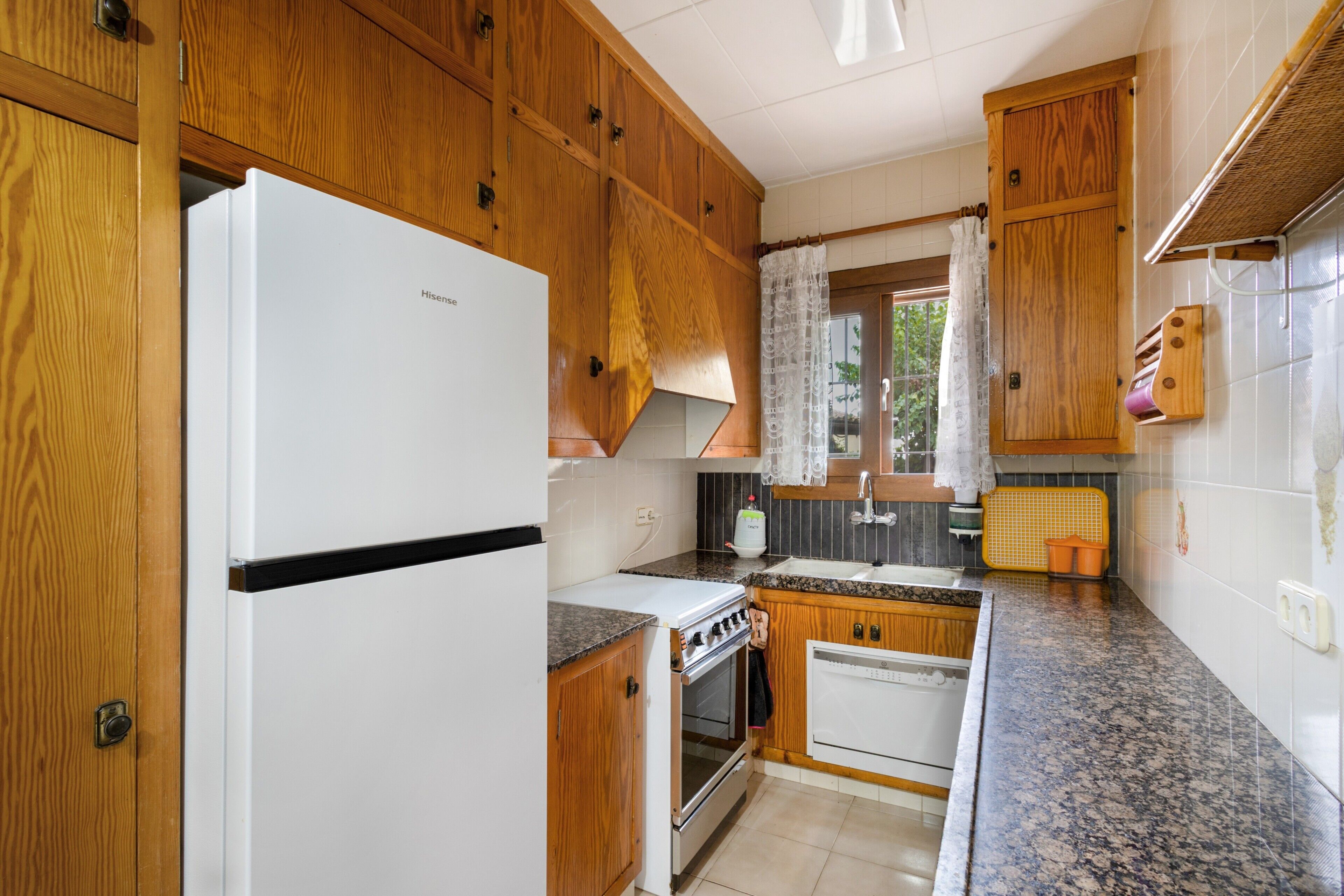 Una cocina con armarios de madera, un refrigerador blanco, una estufa y un fregadero.
