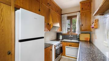 Una cocina con armarios de madera, un refrigerador blanco, una estufa y un fregadero.