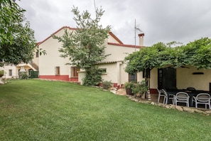 Una casa con techo rojo, fachada blanca y césped bien cuidado.