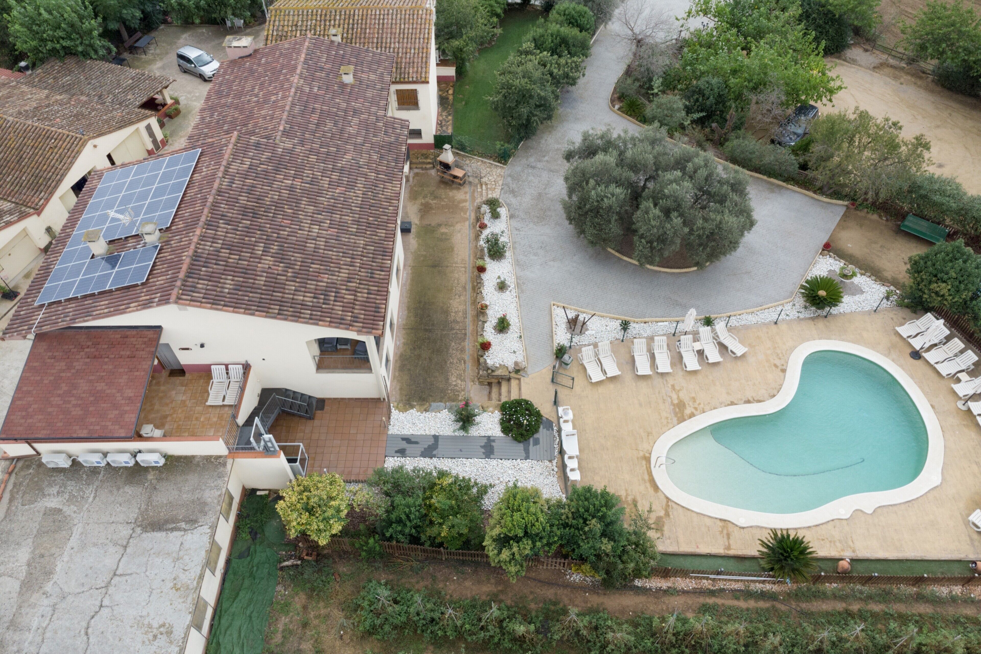 Una propiedad residencial con piscina, paneles solares y jardín.