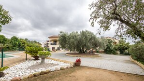 A landscaped courtyard with a pool, potted plants, and a building with a tiled roof.