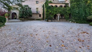 Un bâtiment doté d’une tour en pierre, de fenêtres en arc de cercle et d’une cour recouverte de gravier.