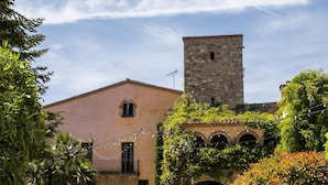 A building with a stone tower, a courtyard, and a garden with various plants.