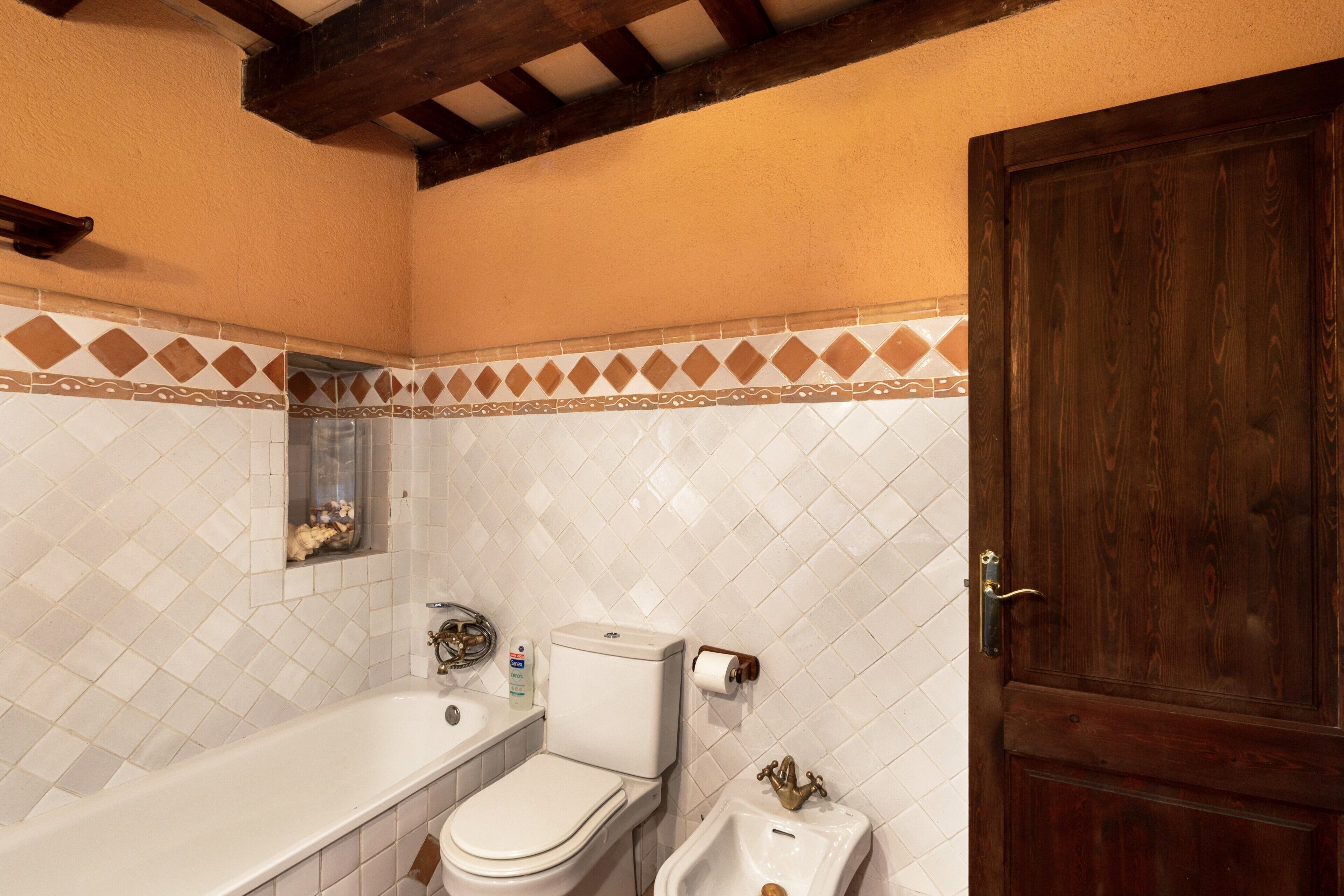 Une salle de bain équipée d’une baignoire, de toilettes, d’un bidet et d’une porte en bois.