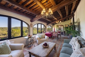 A spacious room with large windows, a wooden ceiling, and a chandelier.