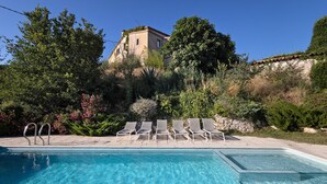 A swimming pool with clear water, surrounded by lounge chairs and a stone wall. - Country House 'Casa Espigol' with Mountain Views, Private Pool and Wi-Fi (El Bruc)