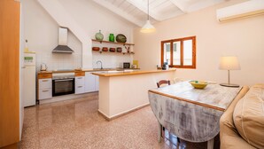 A kitchen with a central island, a dining table, and a sofa. - Apartment 'Can Claret' with Balcony, Wi-Fi and Air Conditioning (Felanitx)