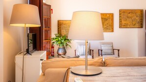 A living room with a sofa, two lamps, a television, a bookshelf, a plant, and two framed maps on the wall. - Apartment 'Can Claret' with Balcony, Wi-Fi and Air Conditioning (Felanitx)