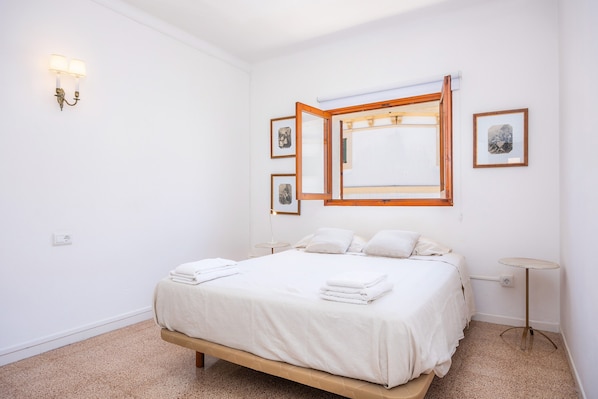 Une chambre à coucher comprenant un lit, une table de chevet, un luminaire fixé au mur et des tableaux encadrés.