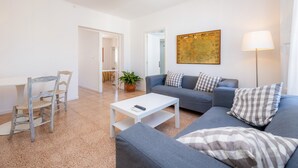 Een moderne woonkamer met een grijze bank, een witte salontafel, een houten stoel en een vloerlamp.