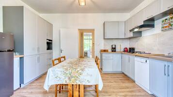 Une cuisine moderne avec des meubles blancs, une table à manger en bois et une vue sur l’espace repas.
