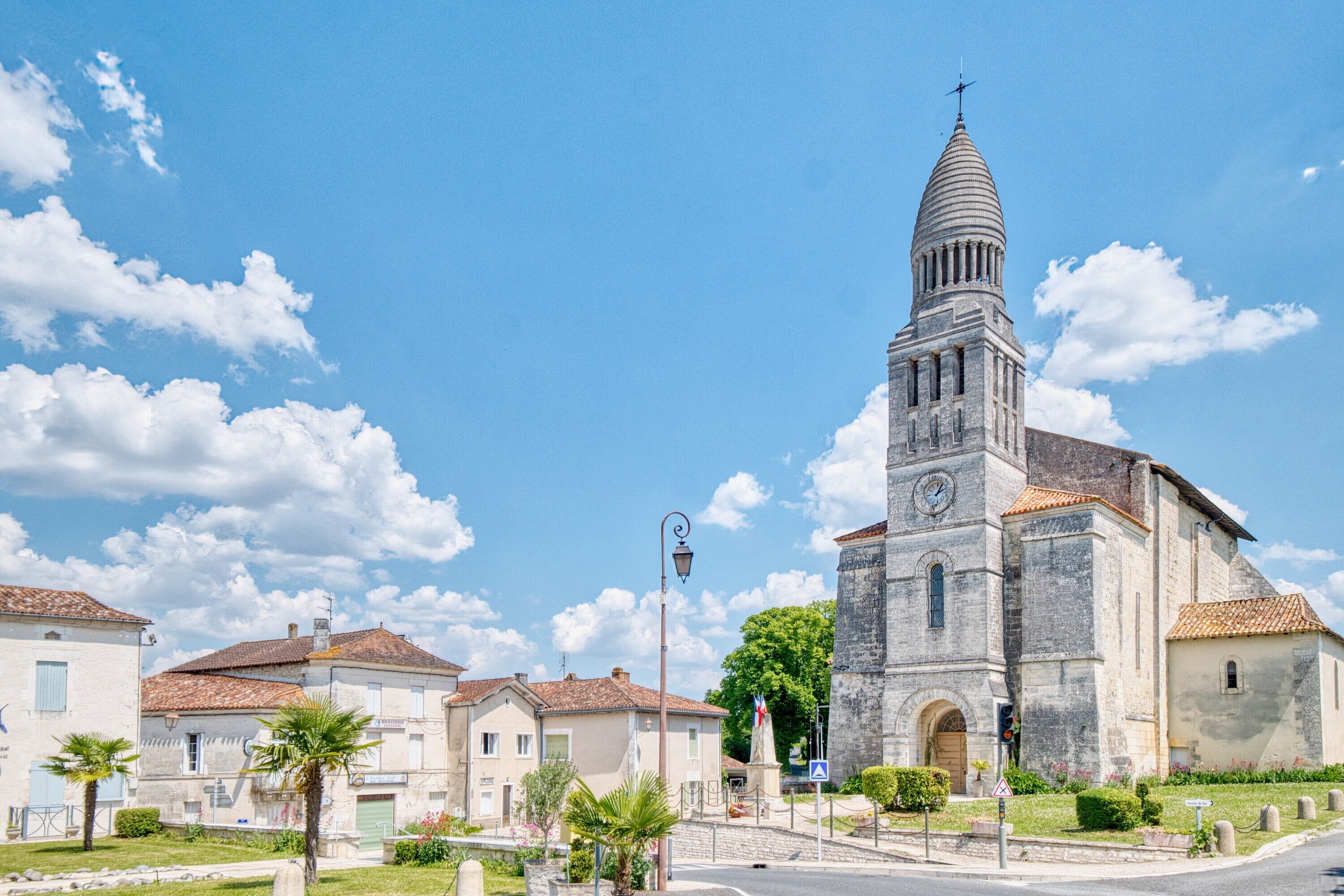 A church with a bell tower, surrounded by residential buildings and a clear sky.
