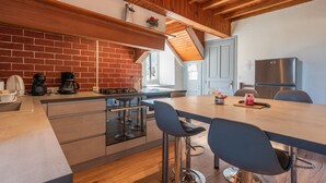 Una cocina moderna con pared de ladrillo, techo de madera y una isla grande con taburetes de bar.