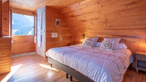 Un dormitorio con paneles de madera, una cama, mesitas de noche y una ventana.
