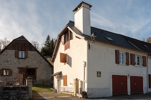 Un bâtiment en pierre avec une porte en bois et un bâtiment blanc avec une cheminée et des fenêtres.