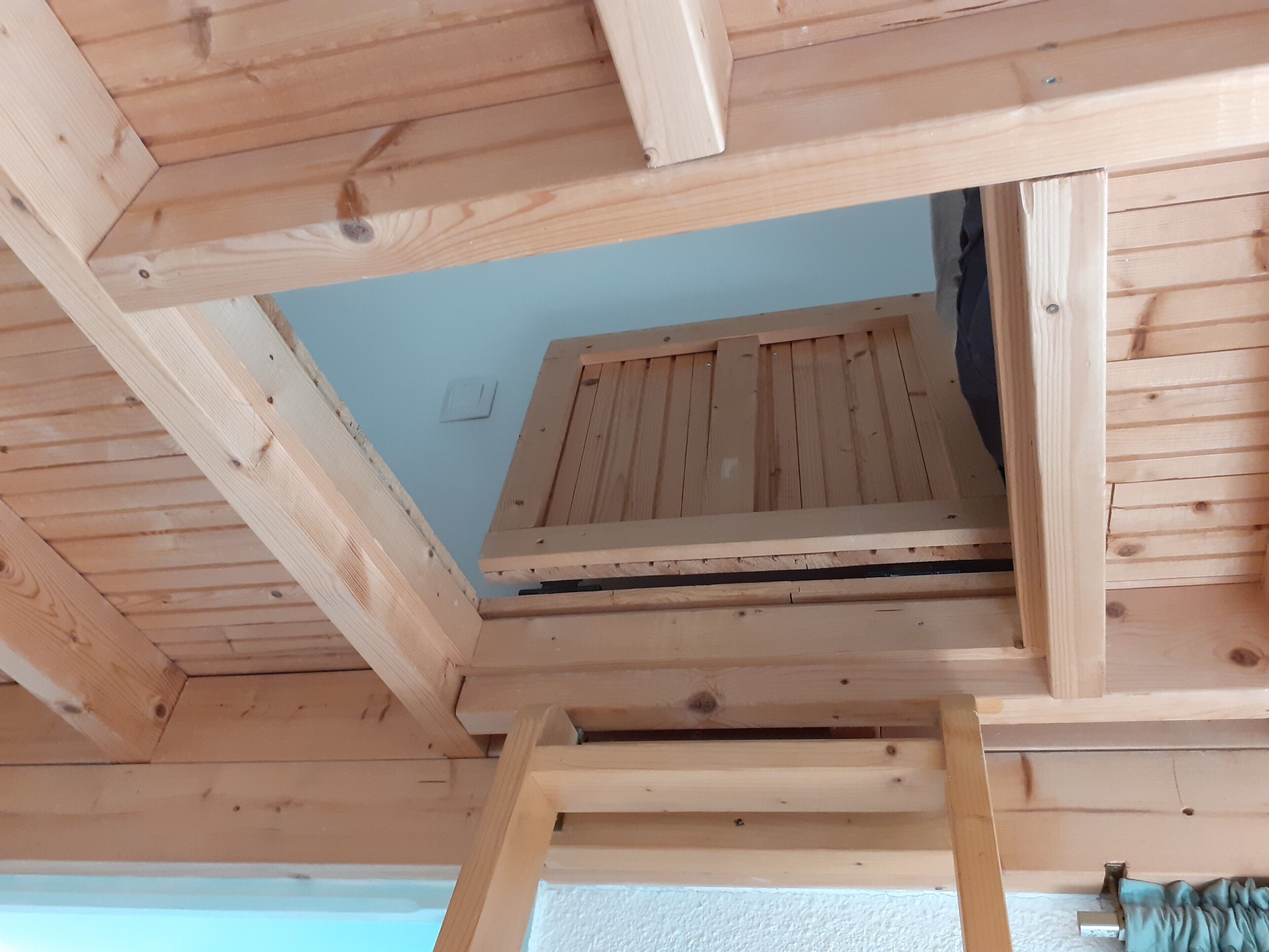 Un ático de madera con tragaluces, una escalera y un interruptor de luz.