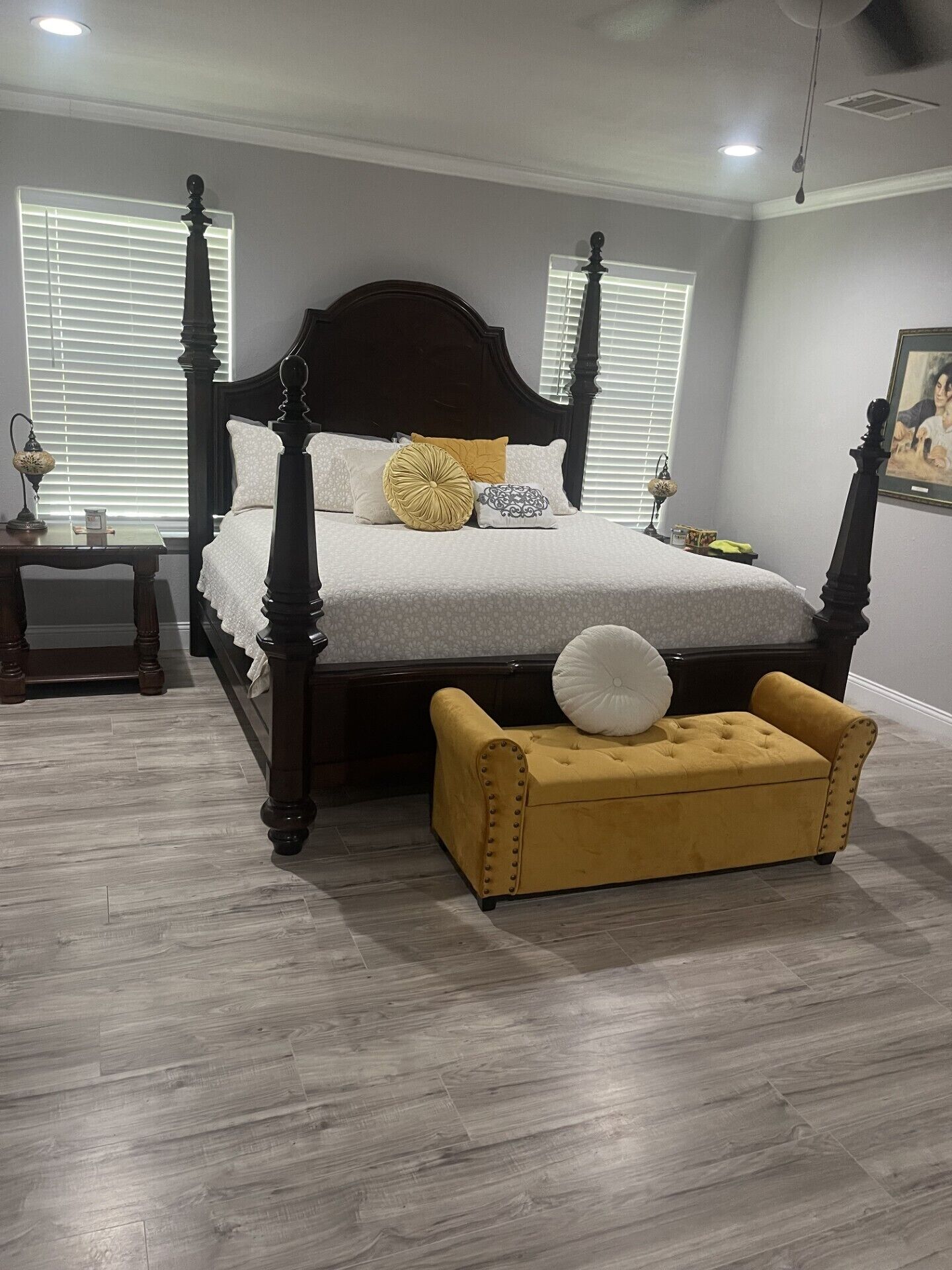 Un dormitorio con cama con dosel, una mesita de noche y un taburete amarillo.