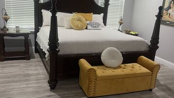 Un dormitorio con cama con dosel, una mesita de noche y un taburete amarillo.