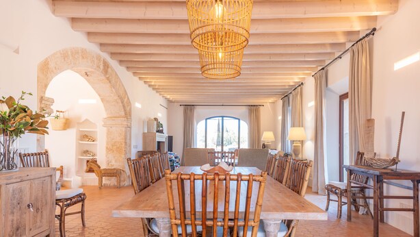 A spacious dining area with a long wooden table, multiple chairs, and a central chandelier. - SON CATXO - Villa with private pool in Búger. Free Wifi. (Búger)